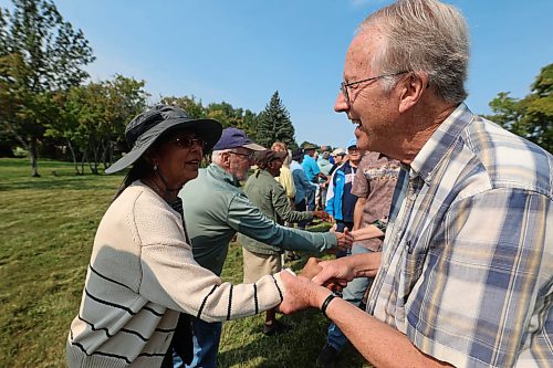 Canadians and Americans shake hands across the 49th parallel to show their support for one another on Saturday. (Alex Lambert/The Brandon Sun)