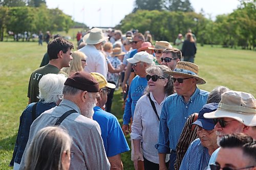 Canadians and Americans straddle the 49th parallel moments before shaking hands to show their support for one another on Saturday. (Alex Lambert/The Brandon Sun)