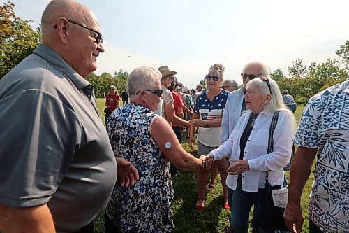 Canadians and Americans shake hands across the 49th parallel to show their support for one another on Saturday. (Alex Lambert/The Brandon Sun)