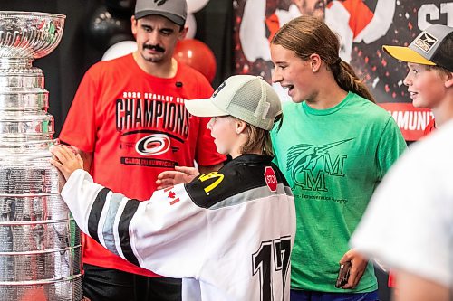 MIKAELA MACKENZIE / FREE PRESS
	
Penny Baldwin (10) and siblings check out the Stanley Cup while taking a photo with Seth Jarvis at the Tuxedo Community Centre on Monday, Aug. 10, 2026.

For Grace Penner story.
Free Press 2026