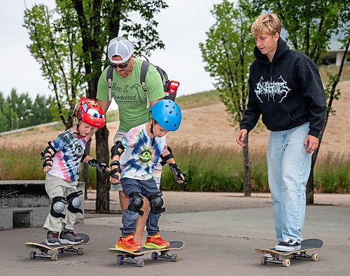 ROBERT LEE / FREE PRESS
Kai (left), 3, and Bodhi, 5, are steadied on their skateboards by their dad, Casey Case while skateboarding instructor Quade Smeall prepares to teach the boys to push off at the skate park at The Forks in Winnipeg on Tuesday, August 11, 2026.