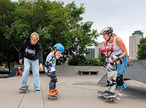 ROBERT LEE / FREE PRESS
Bodhi Case (centre), 5, shows of his skateboarding skills for instructor Quade Smeall, brother Kai, 3, and mother Sandra at the skate park at The Forks in Winnipeg on Tuesday, August 11, 2026. 