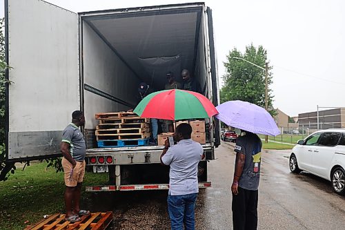 Some residents wait to pick up their pre-ordered boxes of tomatoes despite the rain on Friday morning. The truckload of about 2,000 boxes of Ontario-grown tomatoes arrived in Brandon on Friday, offering residents access to fresh produce at prices below those at some retail stores. (Abiola Odutola/The Brandon Sun)