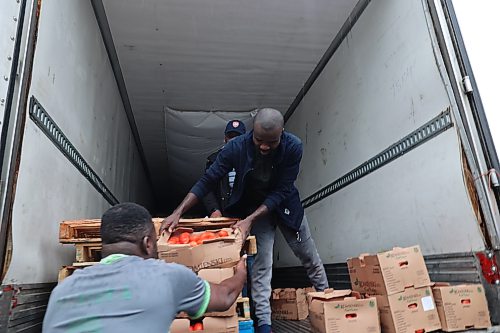 Manaar Logistics owner Sanni Wasiu hands a box of Roma tomatoes to a customer on Friday morning. Wasiu brings about 2,000 boxes of Roma tomatoes to Brandon as part of his growing produce distribution business serving communities across several Canadian provinces. (Abiola Odutola/The Brandon Sun)
