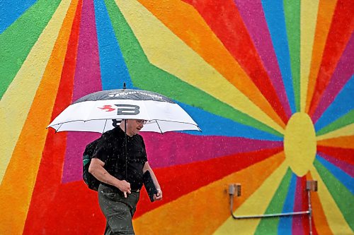 An umbrella-wielding pedestrian passes by a mural in downtown Brandon on a rainy Friday. (Tim Smith/The Brandon Sun)