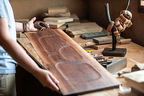 MIKAELA MACKENZIE / FREE PRESS
	
Woodworker Marina Bulan with one of her charcuterie boards in her workshop on Monday, Aug. 17, 2026. She started her business, Cedarella, after taking a cabinetry course at Red River.

For Dave Sanderson story.
Free Press 2026