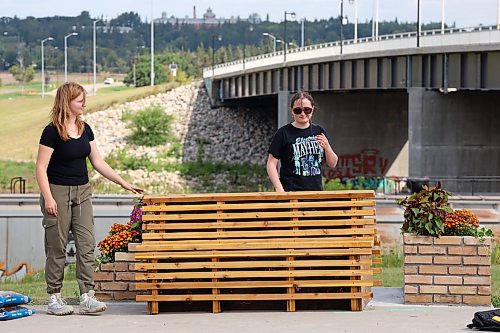 17082026
Landscape architecture student Anastasia Zonenberg and Architecture student Rebecca Grant, both with the University of Manitoba, install a bench as part of their Downtown Outdoor Art Grant creation Station Bloom along Pacific Avenue in Brandon just west of First Street on Monday. The fourth year architecture students applied for the grant earlier this year and their project was chosen as one of several successful downtown arts projects being created this summer. The project is funded by the City of Brandon, Brandon Downtown BIZ and the Brandon Area Community Foundation. The bench and adjacent planters are meant to vaguely resemble the look of a train, as homage to the train yard directly behind the site of the installation. The brick flower bed on the left side of the bench also slopes, pointing towards Brandon’s downtown business district. 
(Tim Smith/The Brandon Sun)