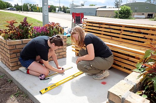 17082026
Architecture student Rebecca Grant and landscape architecture student Anastasia Zonenberg, both with the University of Manitoba, install a bench as part of their Downtown Outdoor Art Grant creation Station Bloom along Pacific Avenue in Brandon just west of First Street on Monday. The fourth year architecture students applied for the grant earlier this year and their project was chosen as one of several successful downtown arts projects being created this summer. The project is funded by the City of Brandon, Brandon Downtown BIZ and the Brandon Area Community Foundation. The bench and adjacent planters are meant to vaguely resemble the look of a train, as homage to the train yard directly behind the site of the installation. The brick flower bed on the left side of the bench also slopes, pointing towards Brandon’s downtown business district.
(Tim Smith/The Brandon Sun)
