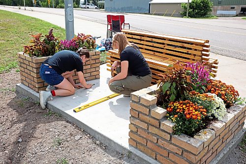 17082026
Architecture student Rebecca Grant and landscape architecture student Anastasia Zonenberg, both with the University of Manitoba, install a bench as part of their Downtown Outdoor Art Grant creation Station Bloom along Pacific Avenue in Brandon just west of First Street on Monday. The fourth year architecture students applied for the grant earlier this year and their project was chosen as one of several successful downtown arts projects being created this summer. The project is funded by the City of Brandon, Brandon Downtown BIZ and the Brandon Area Community Foundation. The bench and adjacent planters are meant to vaguely resemble the look of a train, as homage to the train yard directly behind the site of the installation. The brick flower bed on the left side of the bench also slopes, pointing towards Brandon’s downtown business district. 
(Tim Smith/The Brandon Sun)