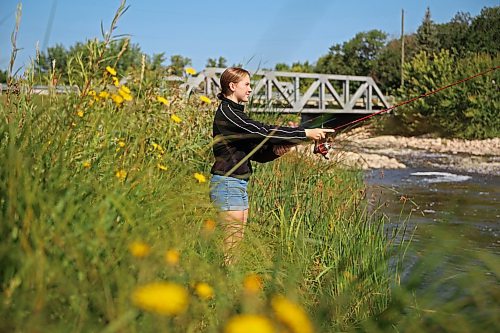 Teagan Helbig fishes from the bank of Plum Creek in Souris on Tuesday while visiting the Westman community with family and friends. (Tim Smith/The Brandon Sun)