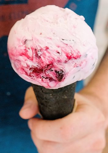 Daniel Crump / Winnipeg Free Press. Chris Kirouac, son of Dug + Betty’s restaurant owner Fern Kirouac, holds a two ice cream cones, strawberry banana (left) and sour cherry dark chocolate (right). June 2, 2020.