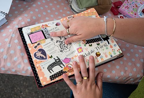 ROBERT LEE / FREE PRESS
Artist and facilitator Katie Borgfjord shows off one of her journals at Scrap & Yap, an arts-and-crafts collage group that has been setting up a table at the Riverview market on Monday, August 24, 2026.