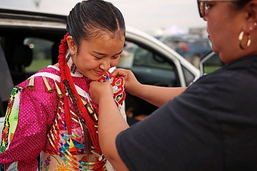 Lesley Snake of a community east of Toronto helps her daughter, Tessa, with her beaded hair ties as Tessa prepares for the grand entry and jingle dancer events. (Tim Smith/The Brandon Sun)
