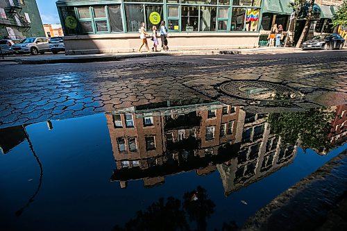 MIKAELA MACKENZIE / FREE PRESS
	
Puddles from recent overnight rain reflect scenes in the Exchange District on Monday, Aug. 31, 2026.

Standup.
Free Press 2026