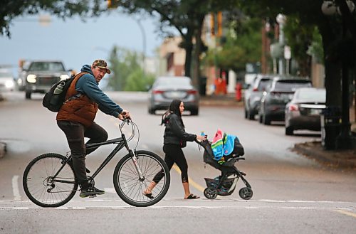 A cyclist and a woman with a baby carriage cross 10th Street at Rosser Avenue shortly after the noon hour on a blustery and cool Thursday afternoon. (Matt Goerzen/The Brandon Sun)