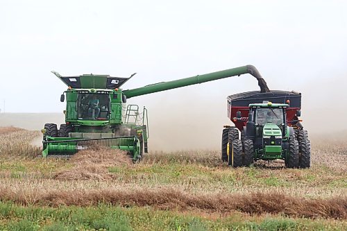 A combine operator unloads a full hopper while harvesting canola in a field north of Boissevain on Friday afternoon. (Matt Goerzen/The Brandon Sun)