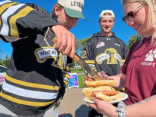 Brandon Wheat King Cameron Allard, left, works the barbeque dishing out hotdogs to a Brandon Humane Society volunteer, supported by fellow Wheat King Nigel Boehm on Sunday morning during the Wag-A-Tail Walk-A-Thon at Kin Park, an annual fundraiser for the Humane Society. (Matt Goerzen/The Brandon Sun)