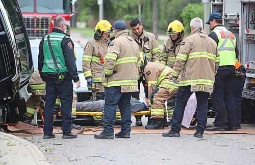 A crew with Brandon Fire and Emergence Services place the driver of a black truck on a stretcher at the corner of Victoria Avenue and Second street after the eastbound vehicle hit a tree on the median and flipped shortly after 1 p.m. on Wednesday, coming to rest on its side, and balanced on the hood of a four-door sedan that was driving behind.  (Matt Goerzen/The Brandon Sun)