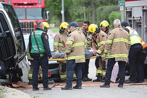 A crew with Brandon Fire and Emergence Services place the driver of a black truck on a stretcher at the corner of Victoria Avenue and Second street after the eastbound vehicle hit a tree on the median and flipped shortly after 1 p.m. on Wednesday, coming to rest on its side, and balanced on the hood of a four-door sedan that was driving behind.  (Matt Goerzen/The Brandon Sun)