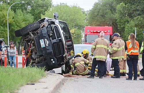 A crew with Brandon Fire and Emergence Services work to free the driver of a black truck that is balanced precariously on the hood of another vehicle at the corner of Victoria Avenue and Second street after the eastbound vehicle hit a tree on the median and flipped shortly after 1 p.m. on Wednesday. The driver was put on a stretcher on scene and taken to hospital. (Matt Goerzen/The Brandon Sun)