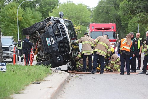 A crew with Brandon Fire and Emergence Services work to free the driver of a black truck that is balanced precariously on the hood of another vehicle at the corner of Victoria Avenue and Second street after the eastbound vehicle hit a tree on the median and flipped shortly after 1 p.m. on Wednesday. The driver was put on a stretcher on scene and taken to hospital. (Matt Goerzen/The Brandon Sun)