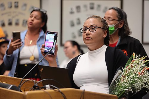 Crystal Delvenne holds up her phone to play audio at the end of a Brandon City Council meeting on Monday (Alex Lambert/The Brandon Sun)