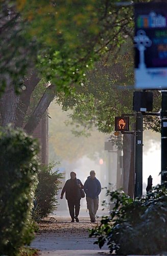 Two people walk the sidewalk west along Princess Avenue on a foggy Thursday morning. (Matt Goerzen/The Brandon Sun)