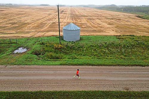 A runner makes their way south from the Birtle Residential School site to Birdtail Sioux First Nation along a grid road while participating in Saturday's run. (Tim Smith/The Brandon Sun)