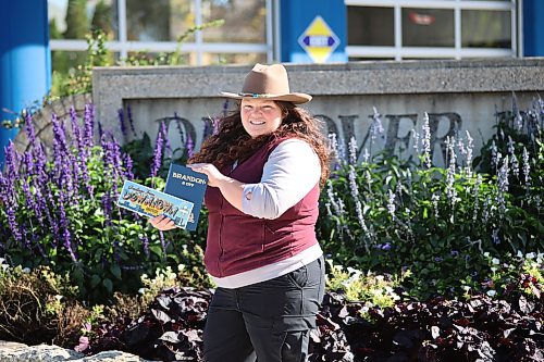Prairie Rovers Tour founder and owner Alison Dawson holds the book "Brandon: A City" on Rosser Avenue on Saturday afternoon. (Abiola Oduola/The Brandon Sun)