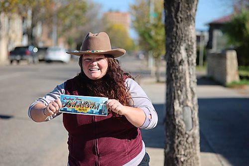 Prairie Rovers Tour founder and owner Alison Dawson holds a "Greetings from Downtown Brandon" card on Rosser Avenue on Saturday afternoon. (Abiola Oduola/The Brandon Sun)