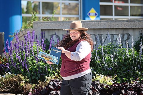 Prairie Rovers Tour founder and owner Alison Dawson holds the book "Brandon: A City" and a "Greetings from Downtown Brandon" card on Rosser Avenue on Saturday afternoon. (Abiola Oduola/The Brandon Sun)
