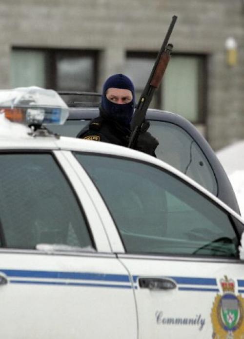 WINNIPEG: JANUARY 1, 2005: STAKE-OUT A police officer holds up his gun and looks around outside of the Stock Exchange Hotel on Saturday morning. Police swarmed the hotel looking for a wanted man. Photo by Marianne Helm/Winnipeg Free Press