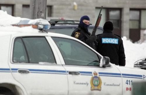 WINNIPEG: JANUARY 1, 2005: STAKE-OUT A police officer holds up his gun and looks around outside of the Stock Exchange Hotel on Saturday morning. Police swarmed the hotel looking for a wanted man. Photo by Marianne Helm/Winnipeg Free Press