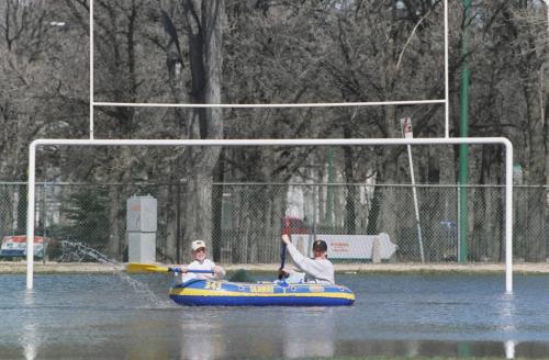 wfp102--winnipeg-- Weather Stand up- Brandon Minceff (L), 14, and John Angst, 15, both Gr.9 students attending Kelvin High School, paddle their way across the water that covers the school's athletic field in an inflatable dinghy. Jeff De Booy photo. Apr.16th/96.--winnipeg free press