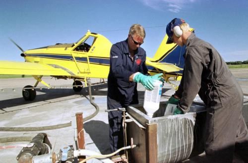 July 7, 1999--Portage la Prairie, MB--John Bodie (left) helps Jason Giercke load chemicals into cropduster Wednesday evening. Bodie runs Jonair which uses six planes to cropdust in the Portage la Prairie area. Photo by Fred Greenslade