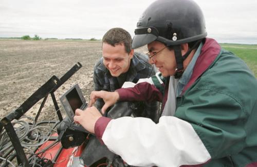 May 21, 1999--Elm Creek, MB--Agronomist Oscar Perez (right) and farmer Darryl Enns look over computer data after Perez drove the ATV loaded up with a global positioning system around his Elm Creek area farm. Perez was checking for weed density Friday. Photo by Fred Greenslade
