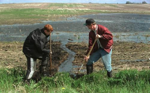 May 24, 1999--Bossevain,MB--Richard Peters (right) and his son Michael dig a ditch to help drain their pea field about 12 miles south of Bossevain Monday. They are digging this field by hand to minimize damage because it is already seeded. Farmers in the area have had trouble seeding because of the Souris River flooding and weeks of rain. PHoto by Fred Greenslade