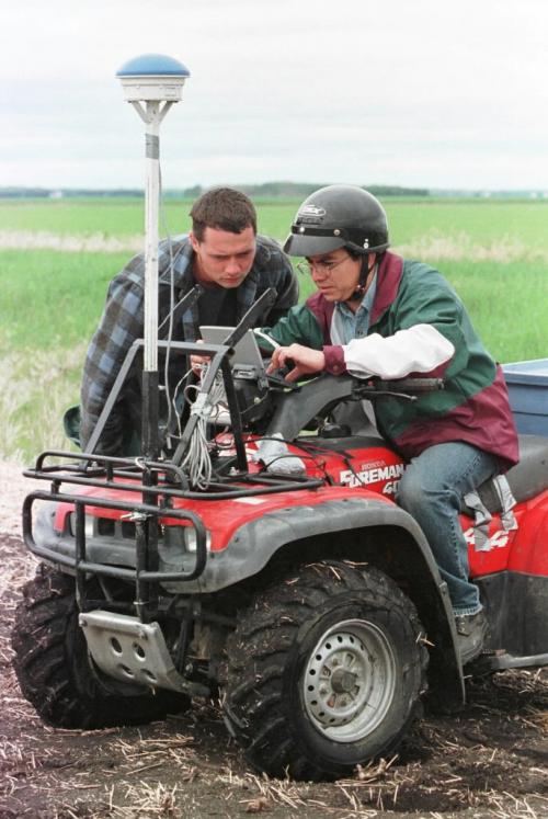 May 21, 1999--Elm Creek, MB--Agronomist Oscar Perez (right) and farmer Darryl Enns look at computer before Perez drives through his Elm Creek area field checking for weed density. Photo by Fred Greenslade